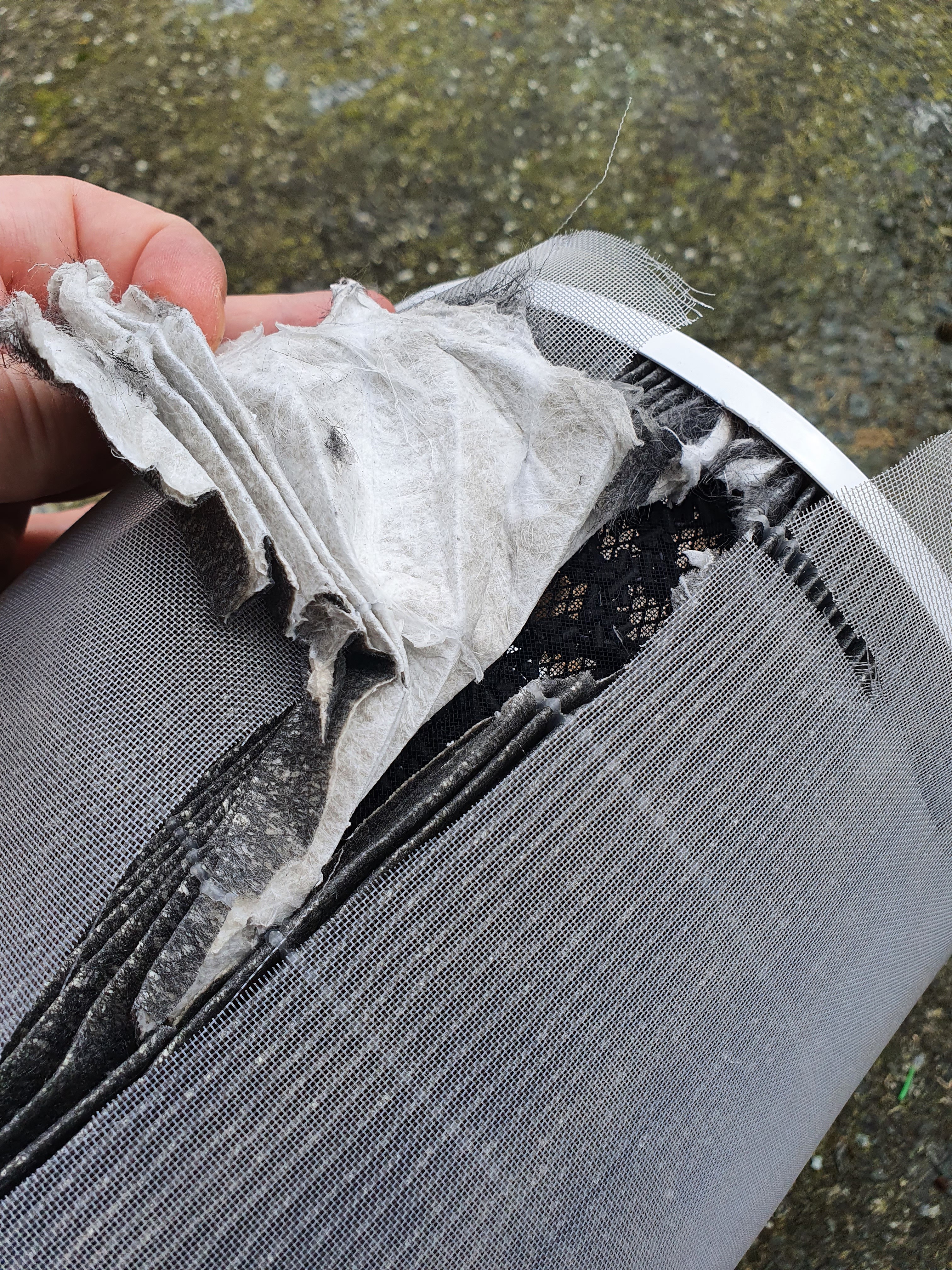 The first layer after the outer plastic grille is a dense paper-like filter thickly folded in concertina. A brand new filter has dark grey outside and I would assume a clean white inside -- this filter has mottled grey outside and obvious discoloration inside. The concertina folding is held taut by a tensioned rubber string which is actually glue, very clever.